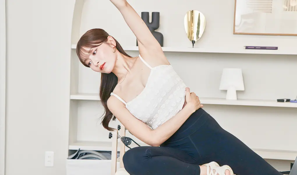 ピラティスマシンで女性がウエストのストレッチをしている様子