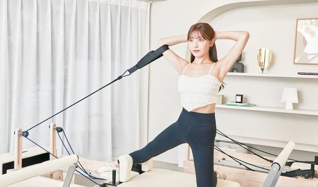 ピラティスマシンで女性がストレッチをしている様子